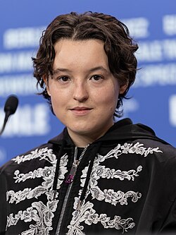 Ramsey in a black jacket with white floral motif, looking ahead