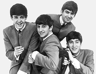 The Beatles smiling for a group photo in matching collarless suits