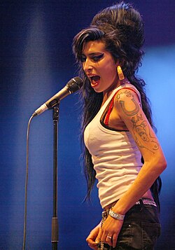 Winehouse singing in front of a microphone, looking down.
