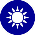 A blue circular emblem on which sits a white sun composed of a circle surrounded by 12 rays