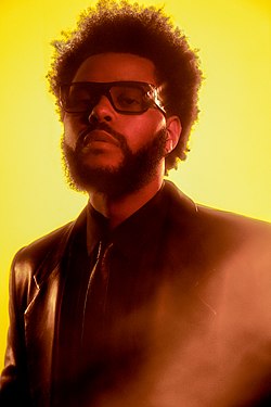 The Weeknd wearing sunglasses and glancing towards a camera